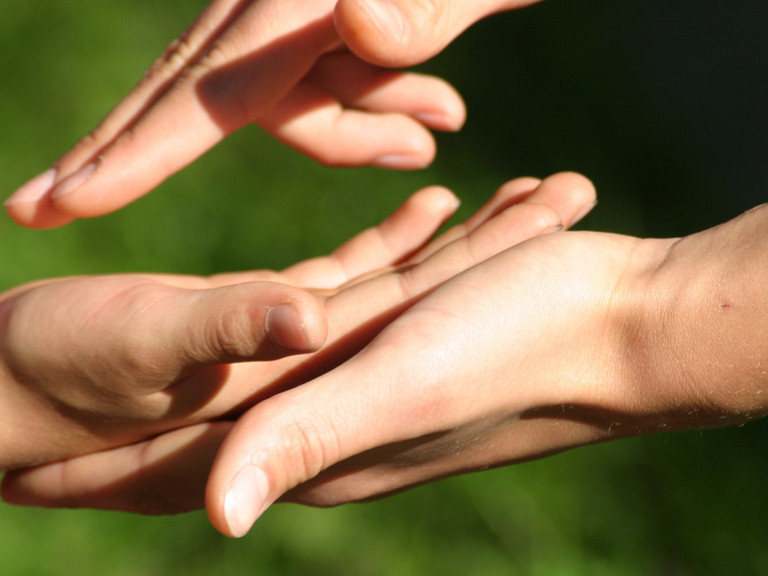 Eine menschliche Hand greift in eine andere und verdeutlicht den Wunsch nach Verständigung Eine menschliche Hand greift in eine andere und verdeutlicht den Wunsch nach Verständigung