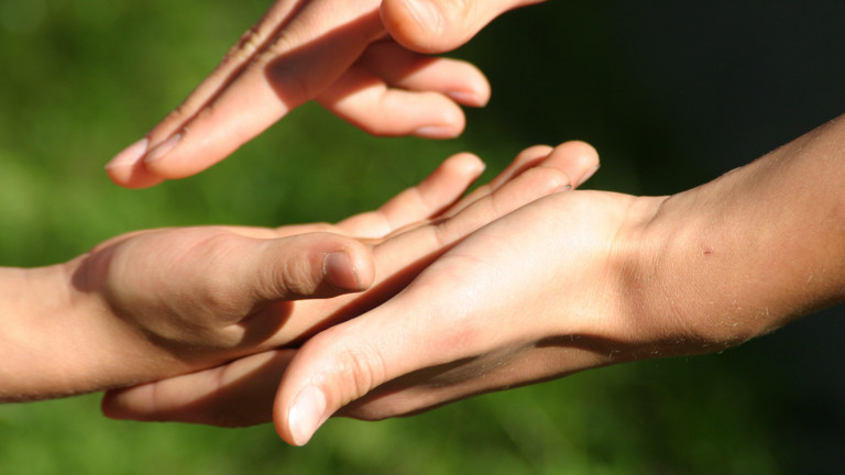 Eine menschliche Hand greift in eine andere und verdeutlicht den Wunsch nach Verständigung