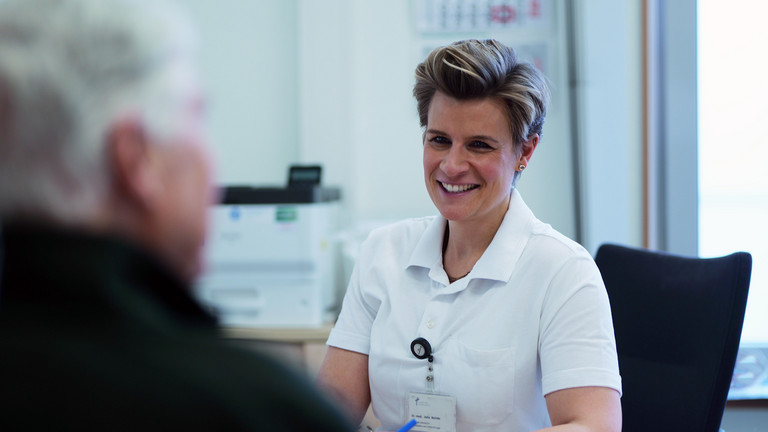 Zentrumsleiterin Dr. med. Julia Reinke sitzt gegenüber eines Patienten bei einem Gespräch im Arztzimmer an einem Schreibtisch im Albertinen Endoprothetikzentrum in Hamburg 